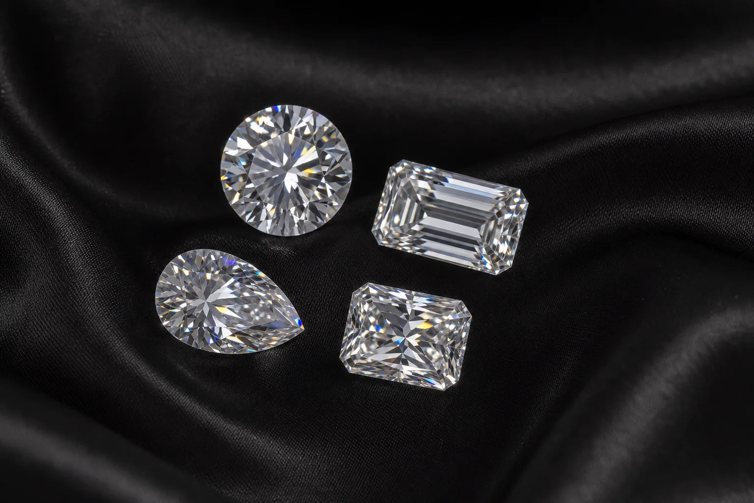 Loose round, emerald, pear and radiant-cut moissanites on black silk